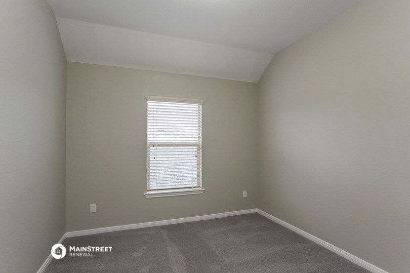 the interior of an empty room with a window and carpet