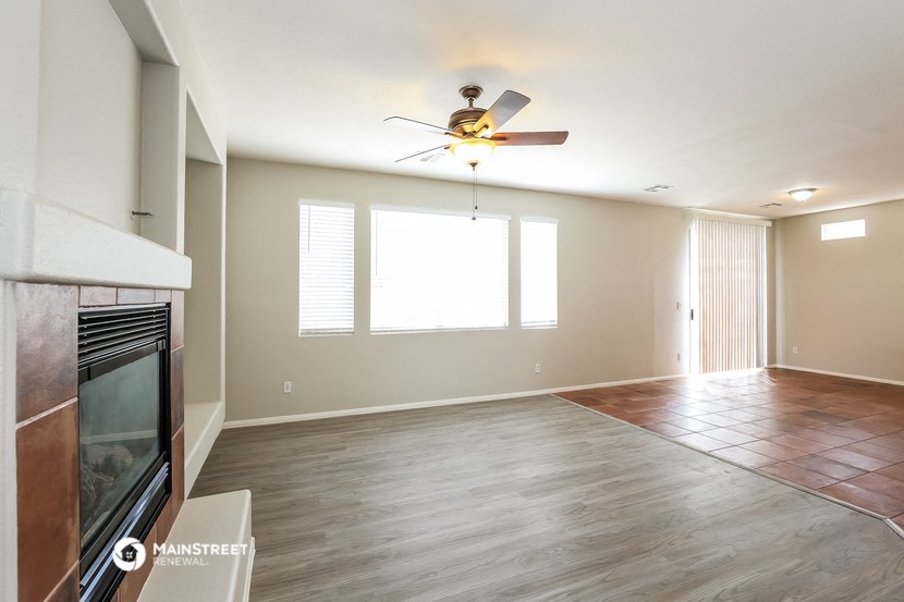 an empty living room with a fireplace and a ceiling fan