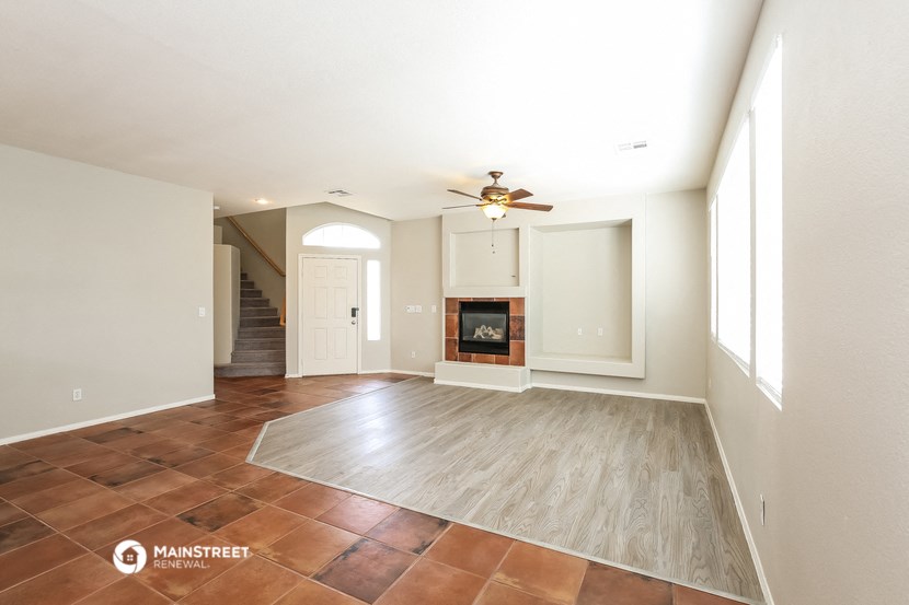 an empty living room with a fireplace and a ceiling fan