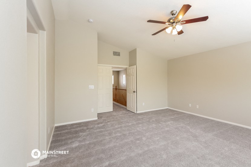 a spacious living room with carpet and a ceiling fan