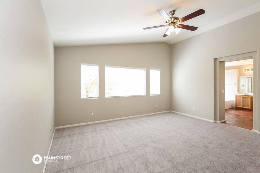 an empty living room with a ceiling fan and a window