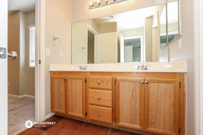 a bathroom with wooden cabinets and a large mirror