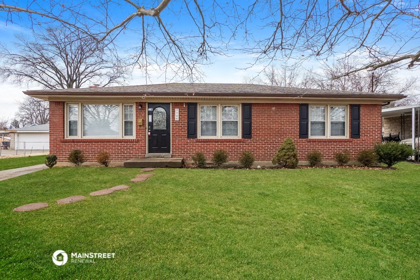 the front of a brick house with a lawn and a black door