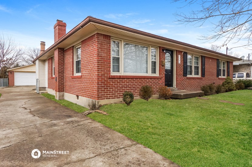 the front of a brick house with a driveway and grass