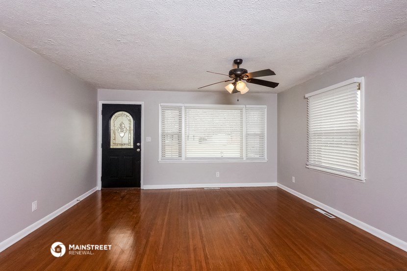 an empty living room with wood floors and a ceiling fan