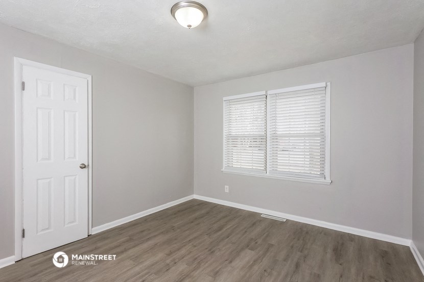an empty living room with a white door and a window