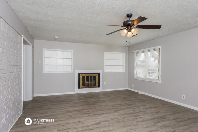 an empty living room with a ceiling fan and a fireplace