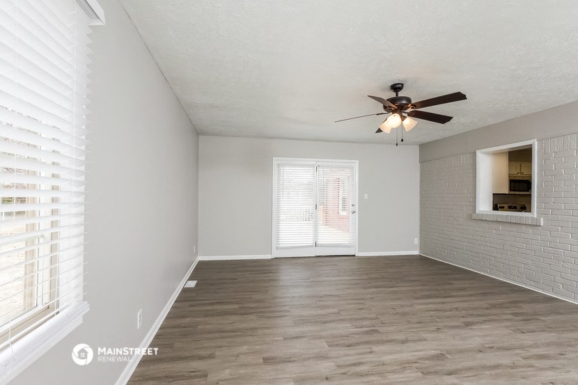 an empty living room with a ceiling fan and a window