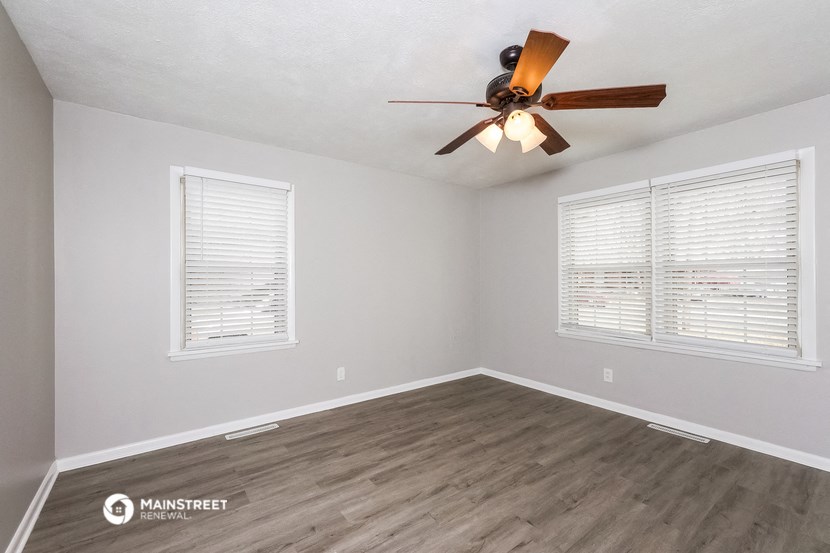 the living room of a home with a ceiling fan and two windows