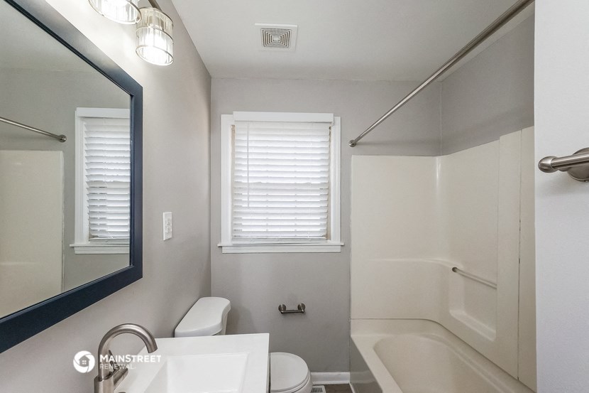 a white bathroom with a mirror and a toilet and a tub