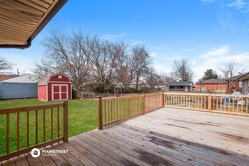 the deck of a home with a red barn in the yard