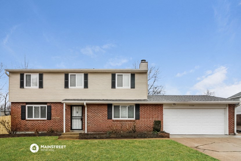 a white house with white garage doors and a lawn