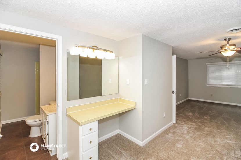 a bathroom with a vanity and a mirror in a room with a toilet and sink