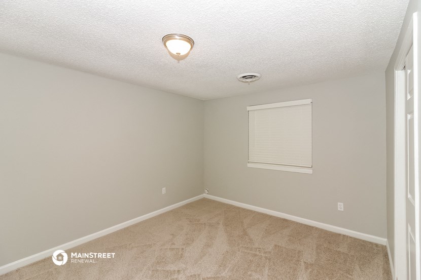 the spacious bedroom of this manufactured home has a large window and beige flooring