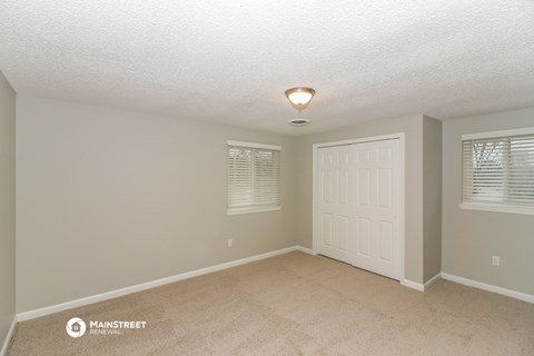 the spacious living room with a white door and beige carpet