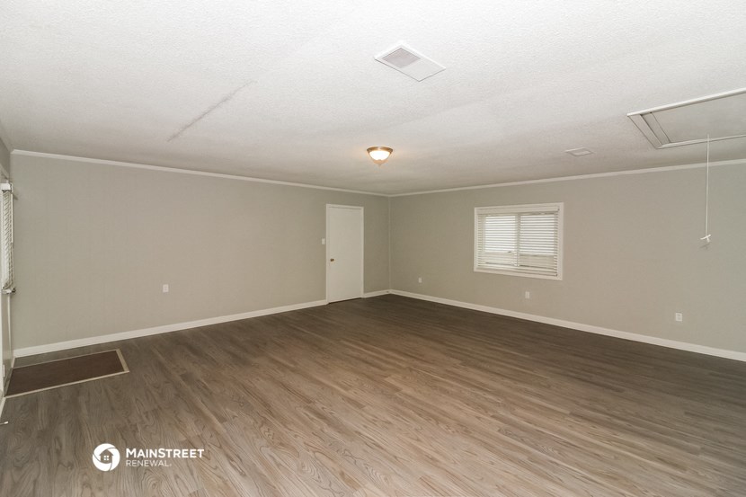 the spacious living room with wood flooring and white walls