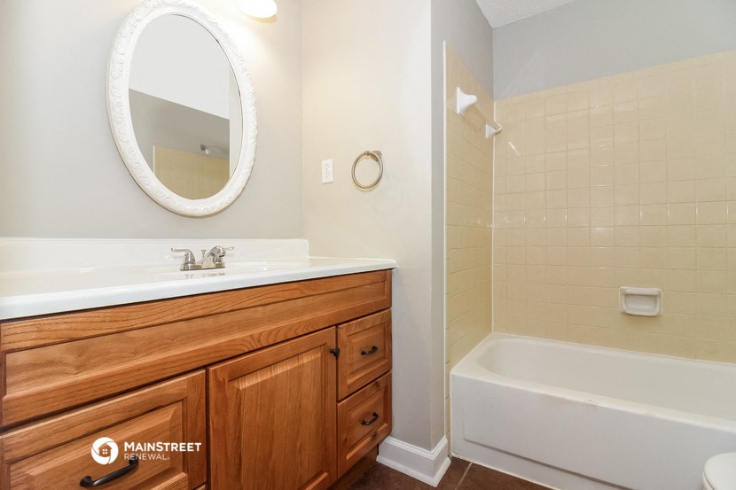 a bathroom with a white tub and a sink and a mirror