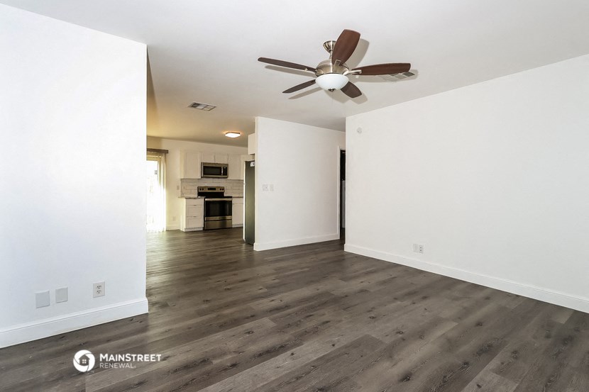an empty living room with white walls and a ceiling fan