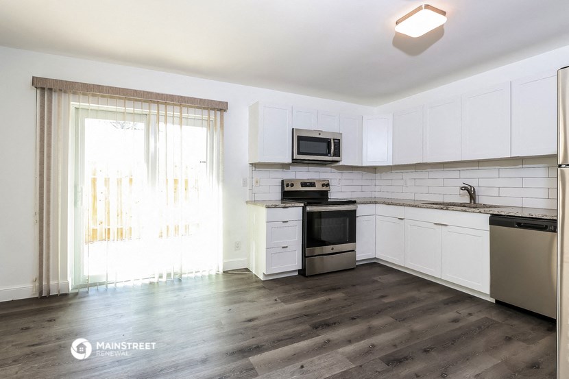 an empty kitchen with white cabinets and stainless steel appliances
