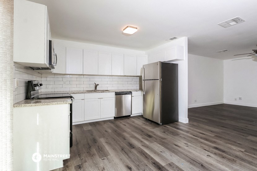 an empty kitchen with white cabinets and a stainless steel refrigerator