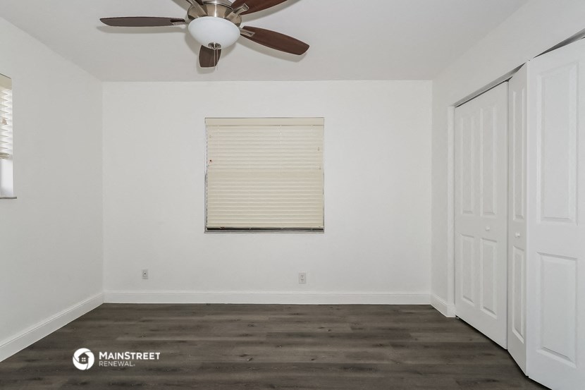 an empty room with a ceiling fan and a window
