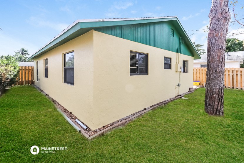 a small house with a green roof and a grassy yard