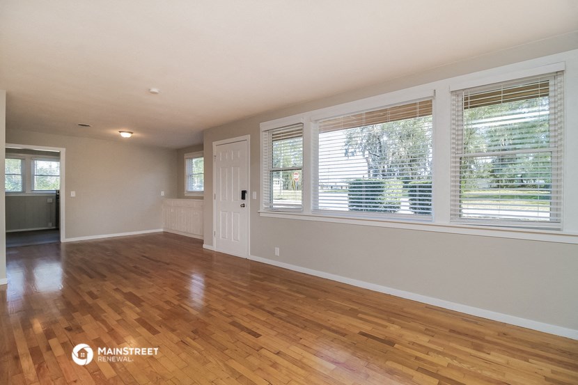 the living room of a house with wood floors and large windows