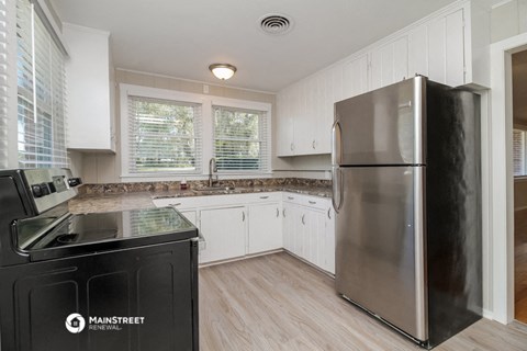 a kitchen with white cabinets and a stainless steel refrigerator