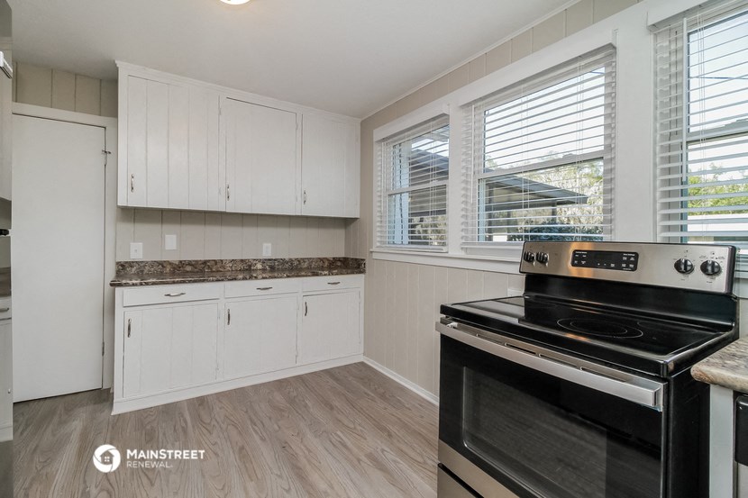 a kitchen with white cabinets and a stove and a window