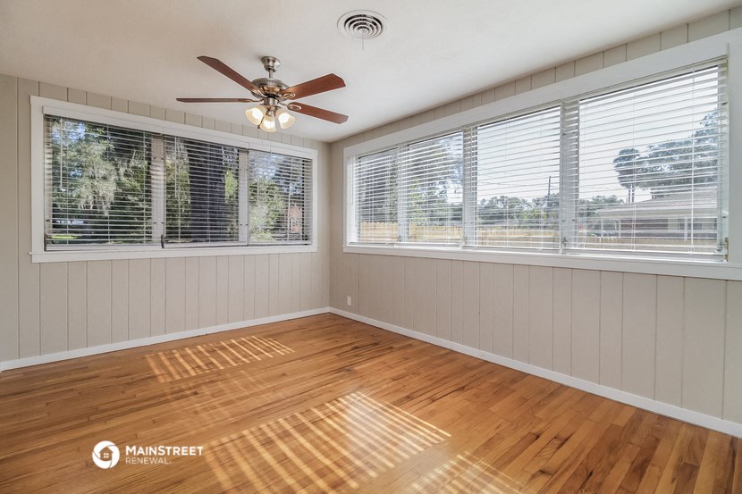 an empty living room with windows and a ceiling fan