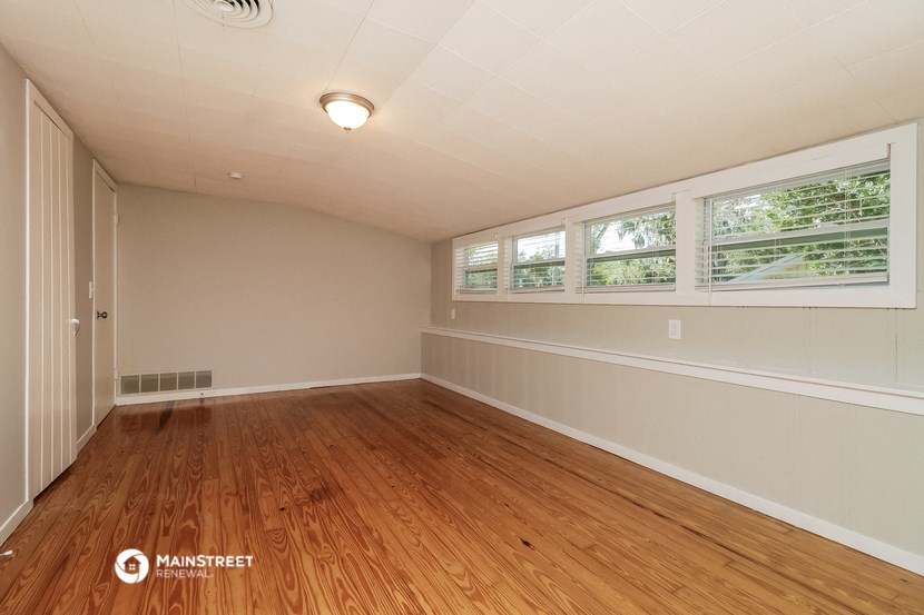 the living room of a house with wood floors and a large window