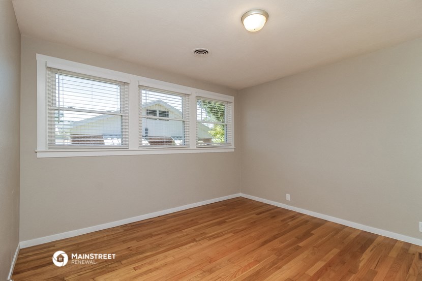 the spacious living room with wood flooring and three windows