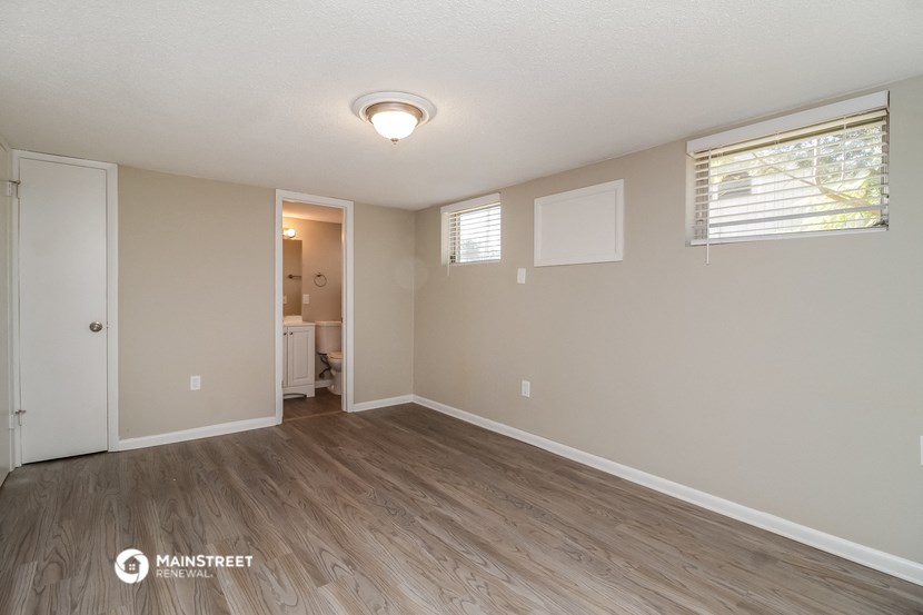 the spacious living room with wood flooring and white walls