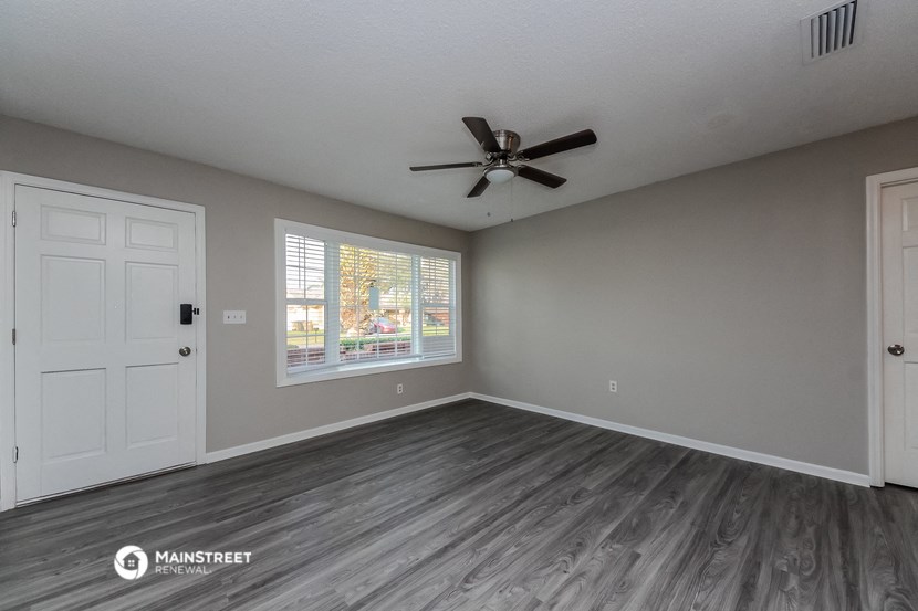 an empty living room with a ceiling fan and a window