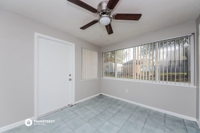 the living room has a large window and a ceiling fan