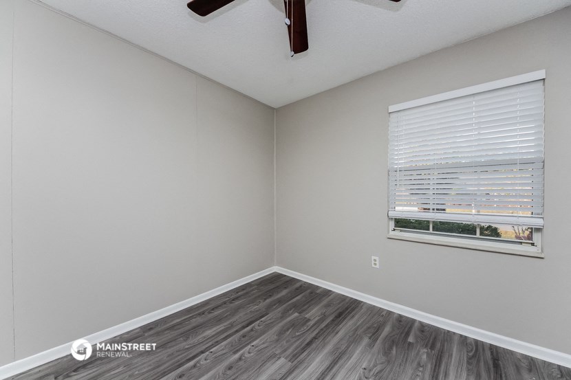 the bedroom of an apartment with wood flooring and a window