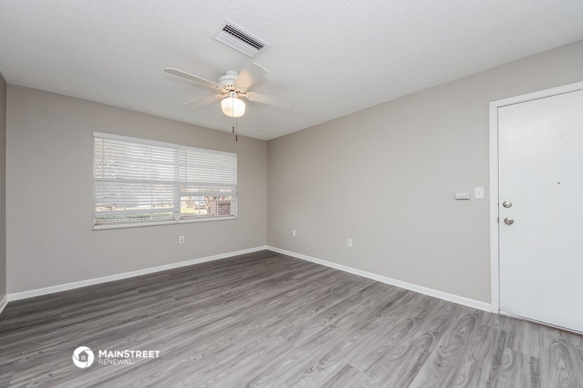the spacious living room with a ceiling fan and a window