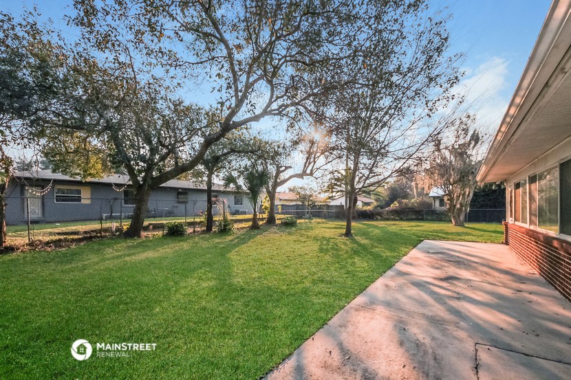 a backyard with trees and a sidewalk and a house