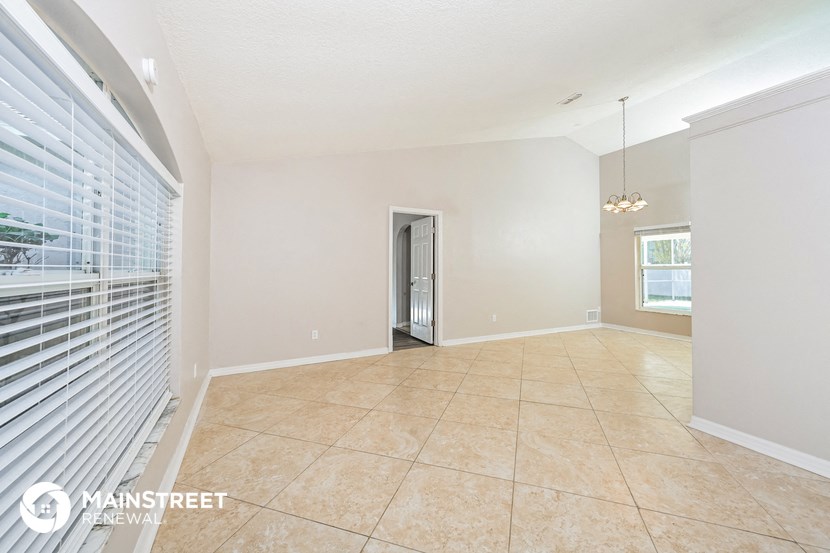 a spacious living room with a large window and a tiled floor