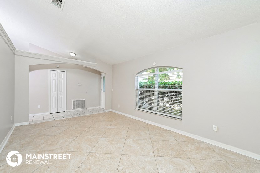 an empty living room with a large window and tile flooring