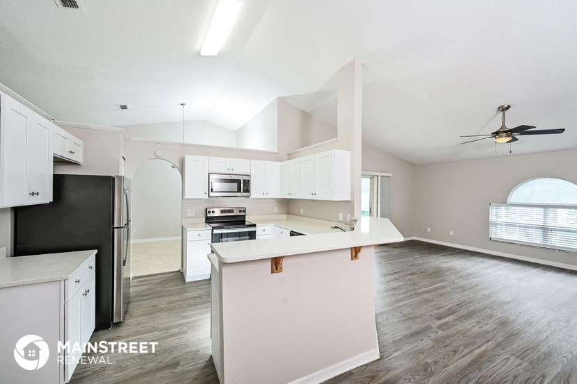 an empty kitchen with white cabinets and a black refrigerator