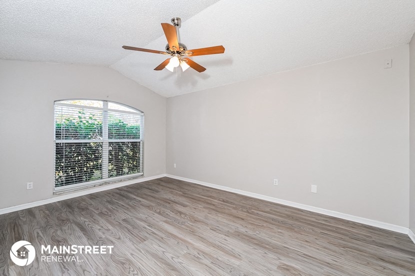 an empty living room with a ceiling fan and a window