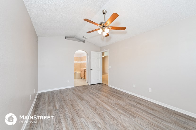 a spacious living room with a ceiling fan and wood flooring