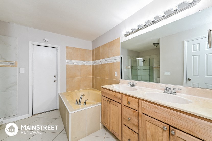 a bathroom with two sinks and a tub and a large mirror