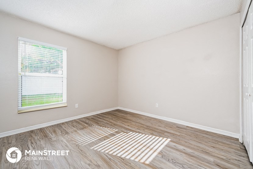 the living room of a small white house with wood floors and a window