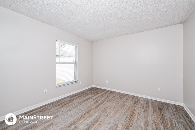 the living room of a small white house with wood flooring