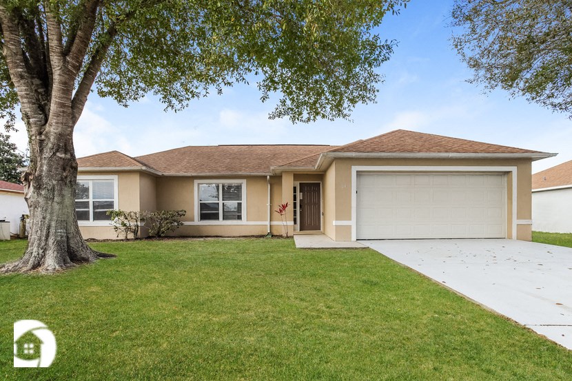 a beige house with a lawn and a tree