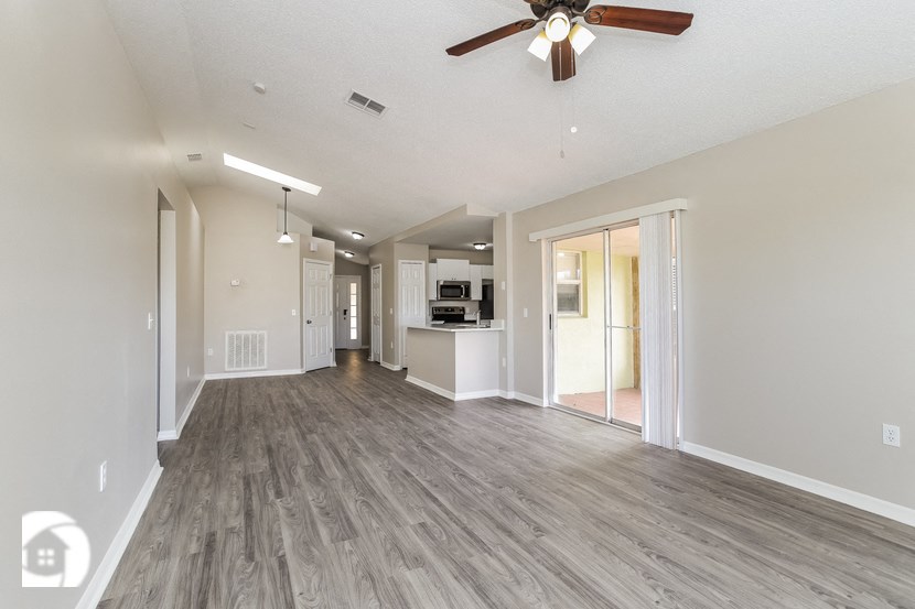 an empty living room and kitchen with a ceiling fan