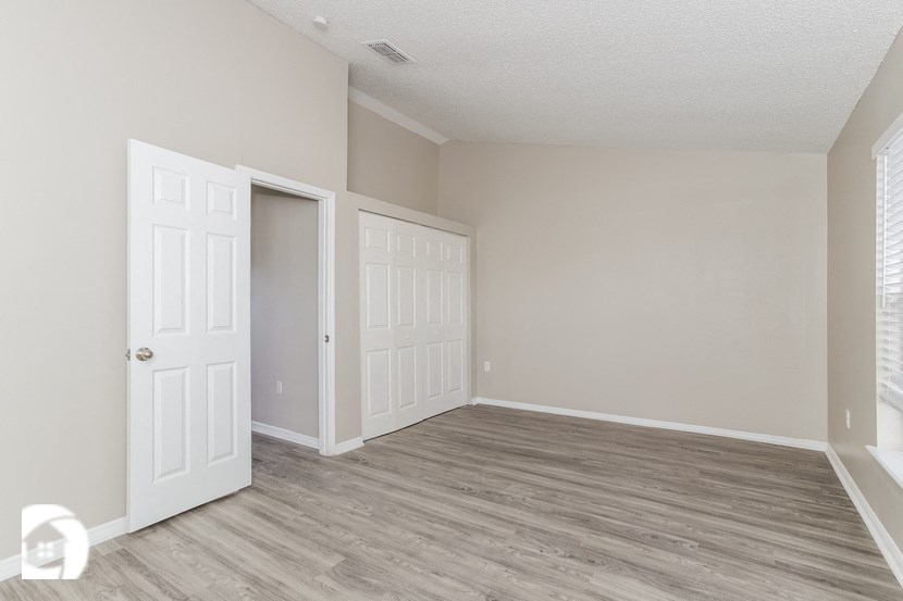 an empty bedroom with two doors and a closet