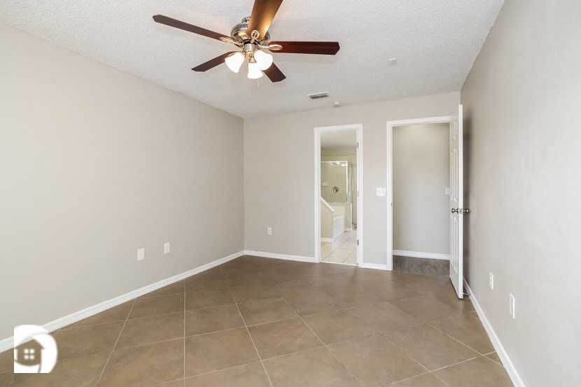 an empty living room with a ceiling fan and tiled floor